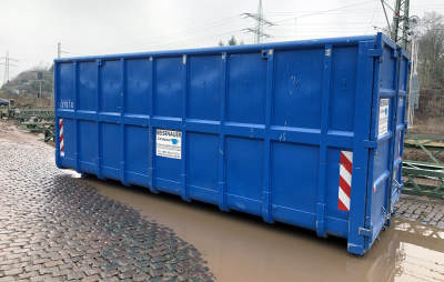 Seitenansicht eines großen blauen Abrollcontainers mit einer Beschriftung 'Reisenauer Container'