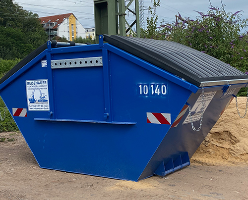 Blauer Absetzcontainer steht auf einer Baustelle neben Baufahrzeugen