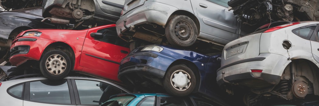 Gestapelte Altfahrzeuge verschiedener Farben auf einem Schrottplatz